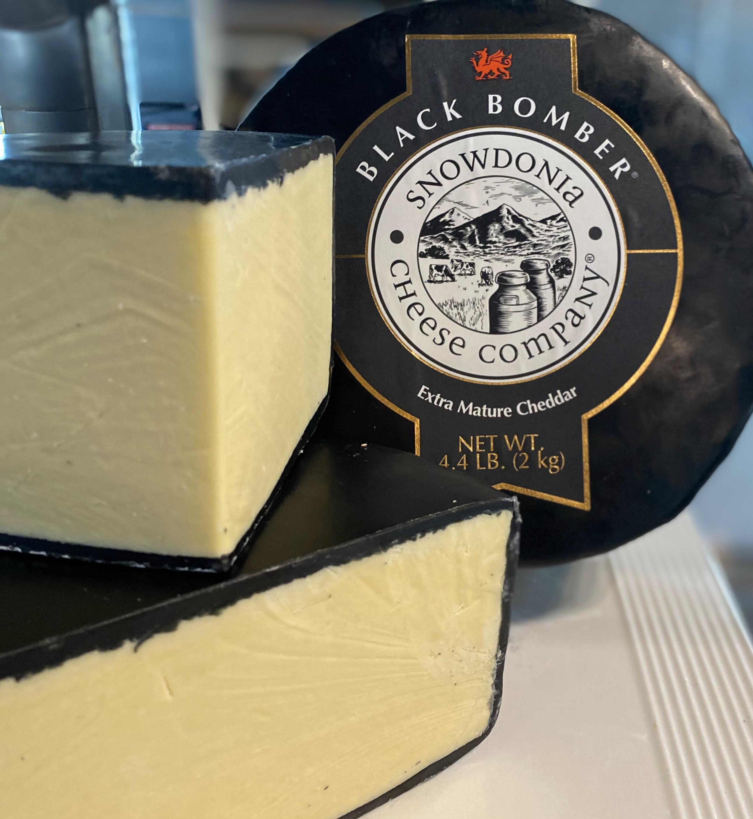 Snowdonia Black Bomber extra-mature cheddar — a black-wax wheel with cut wedges.