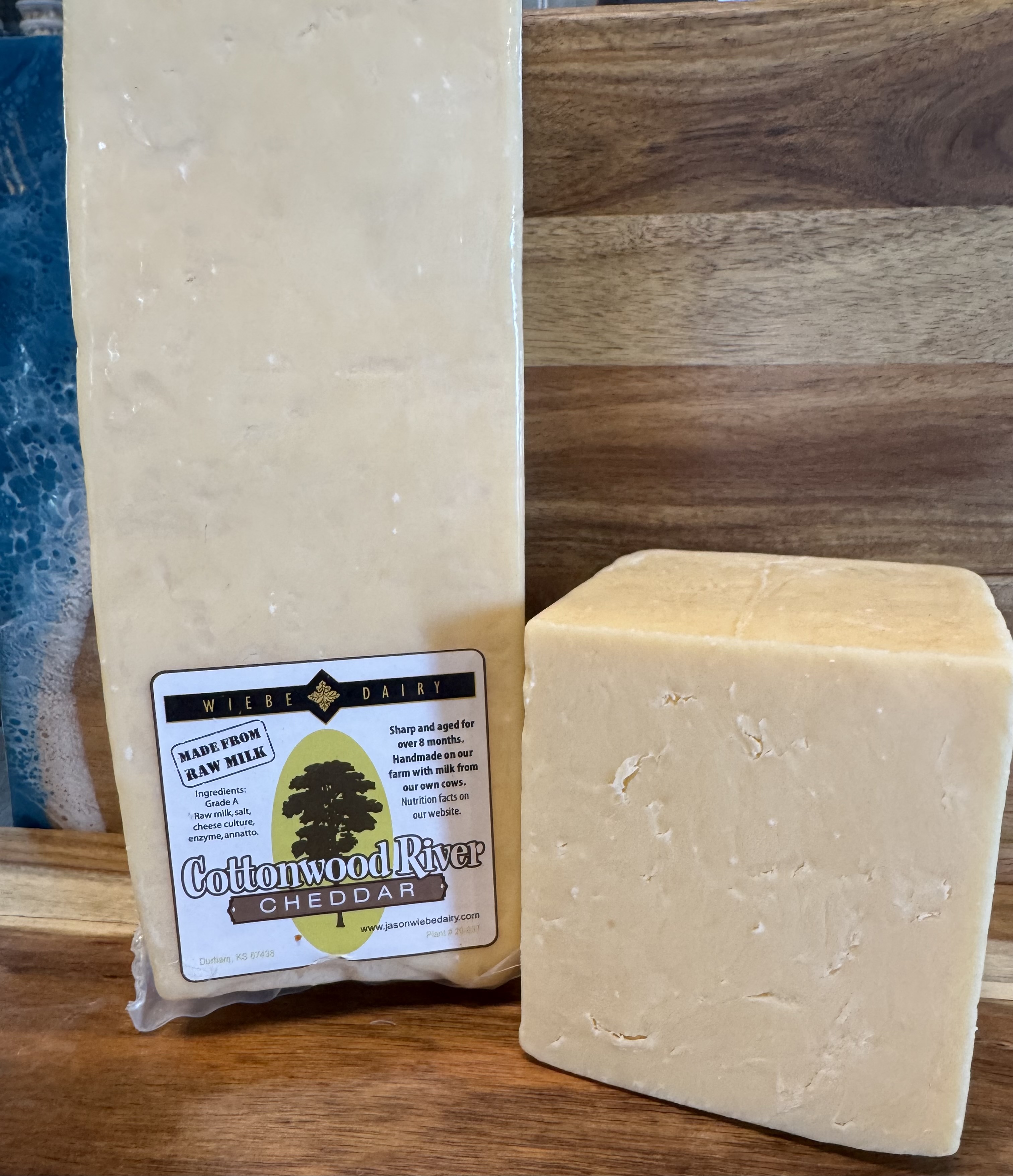 Cottonwood River Cheddar — a labeled block beside a freshly cut cheddar block on a wood board.