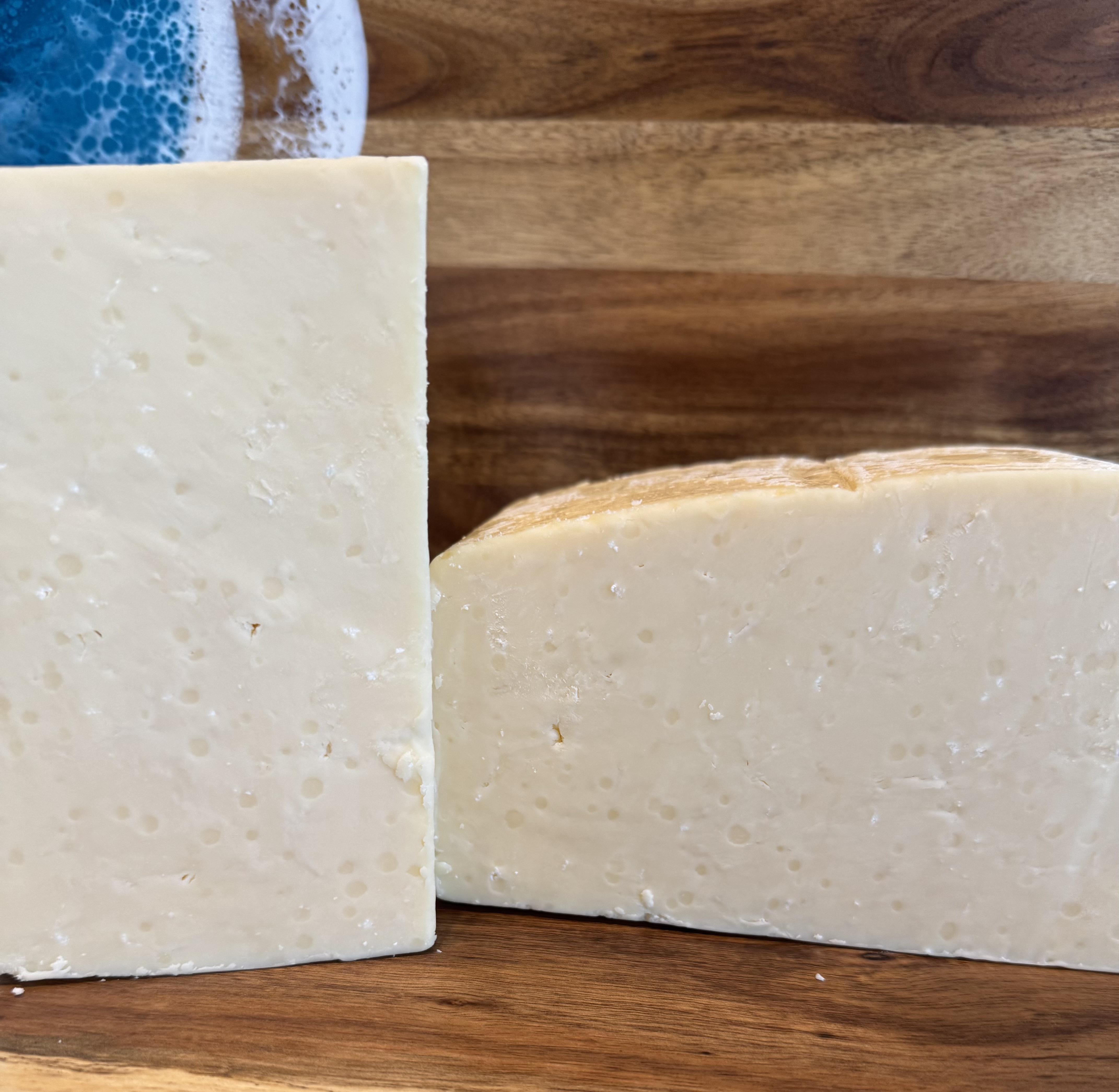 Two pale cut cheese wedges on a wooden board.